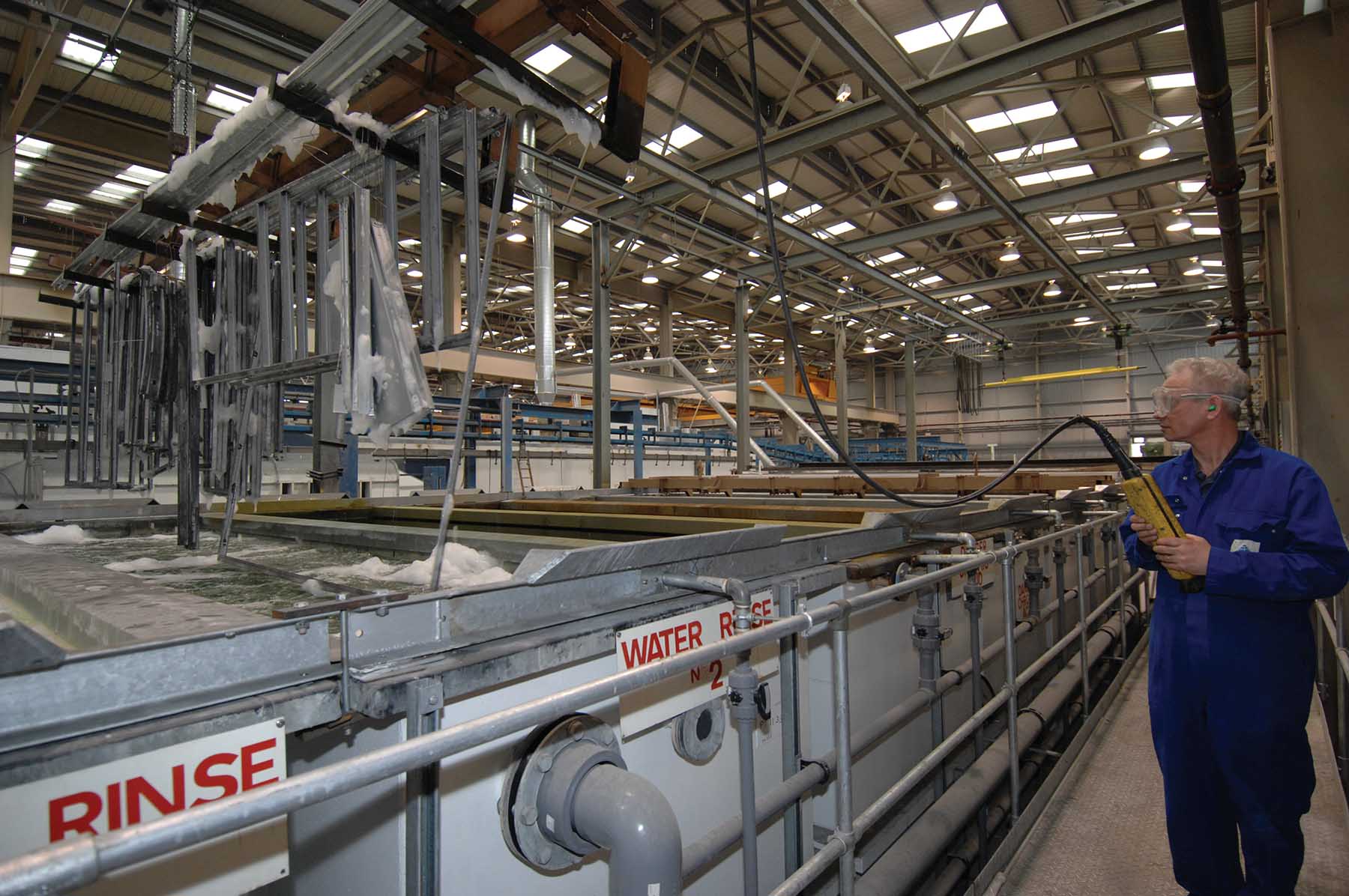 Employee rinsing the steel frames with water